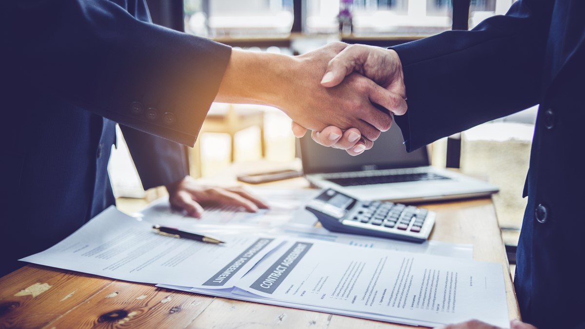 Mãos apertando sobre papel de contratos